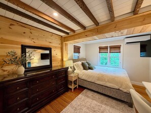 A bedroom with a wooden ceiling, a bed with a white bedspread, a dresser, a mirror, and a window with blinds. - Creekstone House • Walk to Town • Hot Tub + Parking (New Hope)