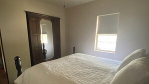 A bedroom with a bed, a ceiling fan, a window, and a door.