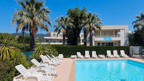 A pool area with lounge chairs, palm trees, and a building with a sign that reads 'ACCEIL'. - Marina Apartment With Terrace (Mandelieu-La-Napoule)