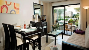 A modern living room with a sofa, dining table, chairs, a TV, and a balcony with a view of the city. - Marina Apartment With Terrace (Mandelieu-La-Napoule)