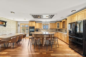 A modern kitchen with a central island, wooden cabinets, and a large refrigerator. - Hudson Retreat, Pool, Spa, Game Room, Gym (Gardiner)