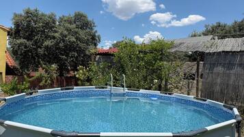Una piscina amb un videt de rajola blava, envoltada d'arbres i una tanca de fusta.