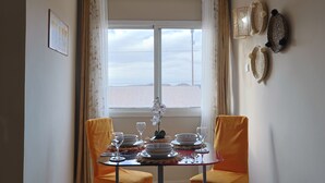 A dining area with a table set for four, two chairs, a window with curtains, and wall decor. - Appartement Moderne au Centre-Ville Guéliz (Marrakech)
