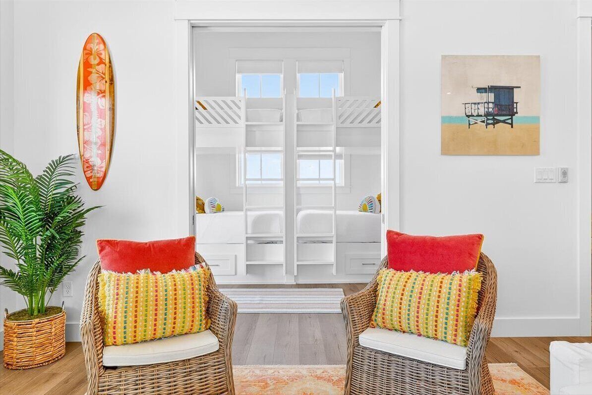 Una habitación con sillas de mimbre, una tabla de surf y un cuadro con motivos playeros.
