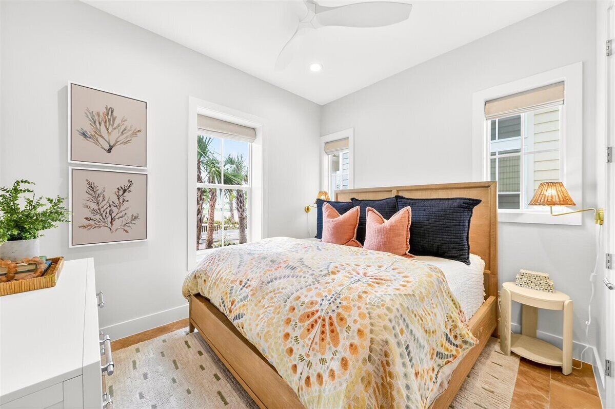 Un dormitorio con cama, mesita de noche, lámpara y ventana.