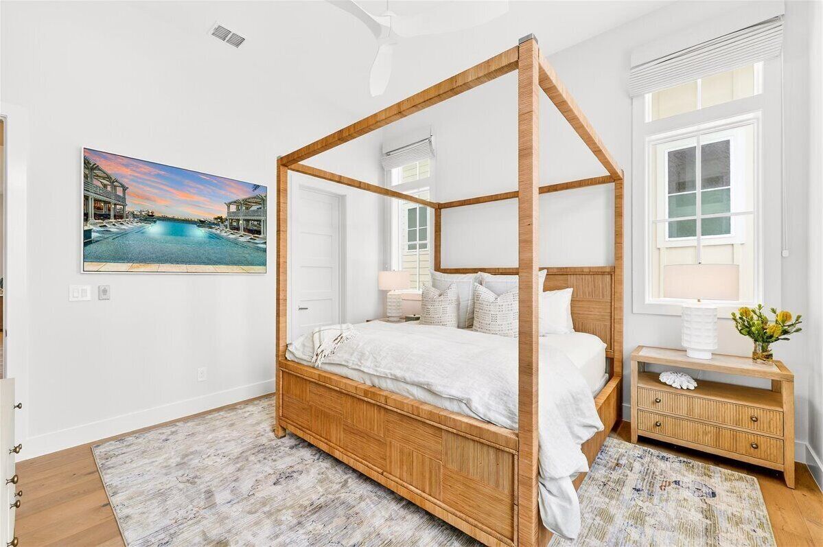 A four-poster bed with a wooden frame, a white bedspread, and a nightstand with a lamp and decorative items.