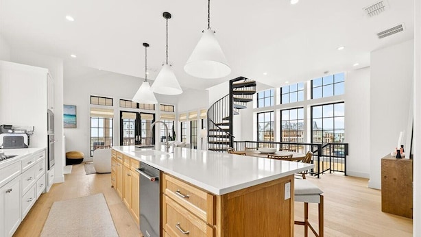 A modern kitchen with a central island, pendant lights, a spiral staircase, and large windows. - The Little Dipper - 100 STL (Port Aransas)