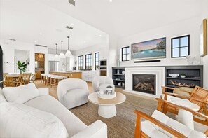 Ein geräumiges Wohnzimmer mit Kamin, Essbereich und einer Küche im Hintergrund.