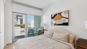 Um quarto com cama, mesa de cabeceira, luminária e um quadro na parede.