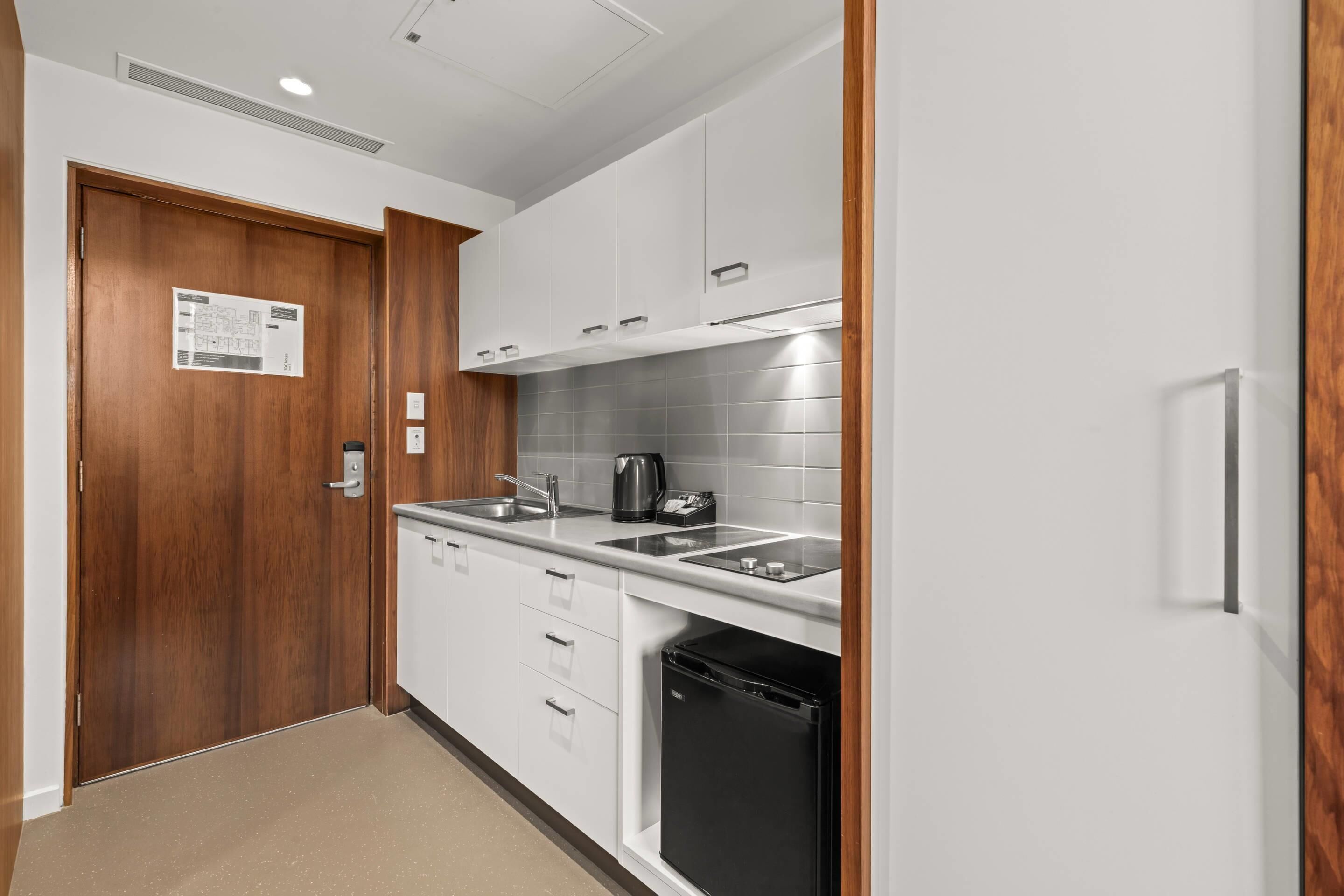 Una cocina moderna con armarios blancos, un lavavajillas negro y un lavabo de acero inoxidable.