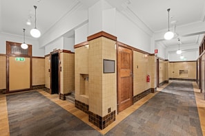 A hotel restroom with multiple stalls, a fire extinguisher, and a 'CLEANER' sign on the wall. - Comfort Inn Geelong (Geelong)