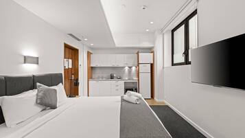 Una habitación de hotel con cama, televisión, kitchenette y baño.