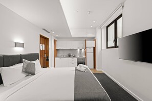 Een hotelkamer met een bed, een televisie, een kitchenette en een badkamer.