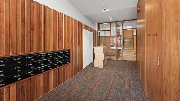 A hallway with wooden paneling, a fire panel, a security camera, and a fire alarm.