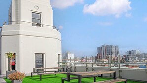 A modern building with a clock tower, green artificial grass, and benches.