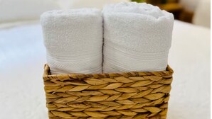 A woven basket containing two neatly folded white towels. - Suite 02 • Spacious Suite • Boutique Mansion (Guayaquil)