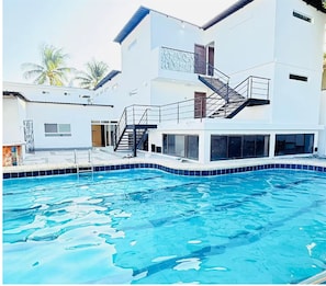 Ein Schwimmbad mit einem modernen Gebäude im Hintergrund.