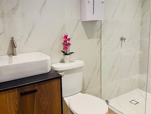 Ein Badezimmer mit weißem Waschbecken, einer Toilette und einer Dusche.