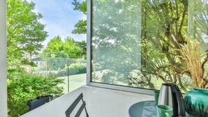 A balcony with a view of a tennis court, a table with a chair, and a vase with dried plants. - Lavignottes - AC - Piscine & Tennis (Labouheyre)