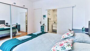 A bedroom with a bed, a desk, a mirror, and a bathroom visible through an open door. - Lavignottes - AC - Piscine & Tennis (Labouheyre)