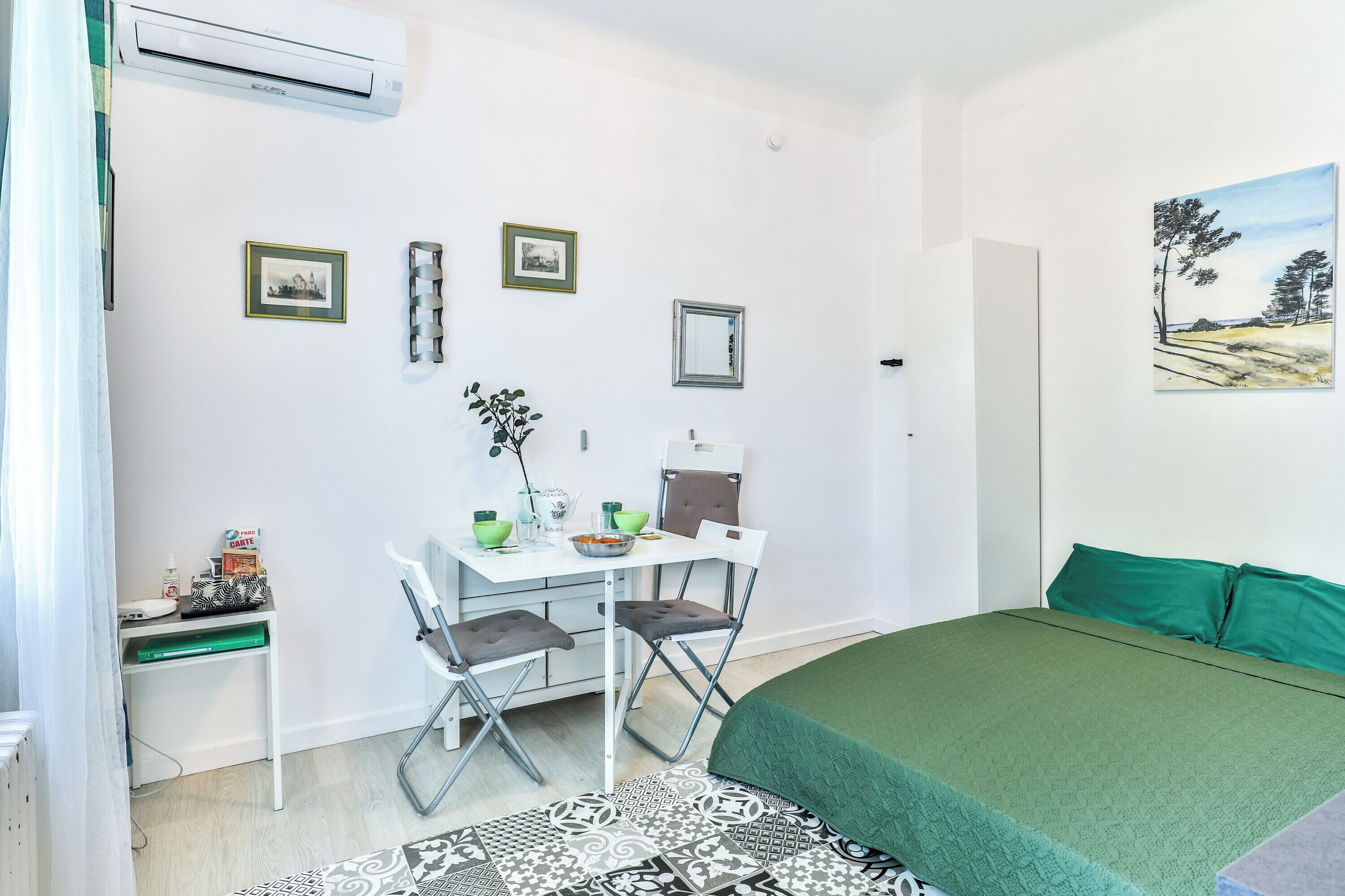 Une petite pièce propre, avec un lit, un bureau, une chaise et un tableau accroché au mur.