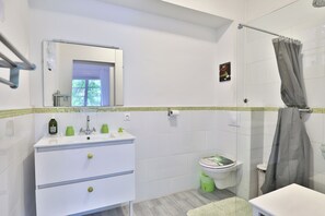 A bathroom with a white sink, mirror, toilet, and shower curtain. - Lavignottes - AC - Piscine & Tennis (Labouheyre)