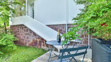 A patio with a table and chairs, a bottle of champagne, and a stone wall.