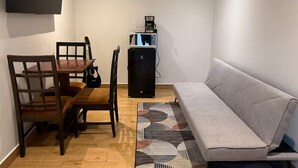Un espace de vie compact comprenant une table à manger, des chaises, un canapé, une machine à café et un téléviseur.