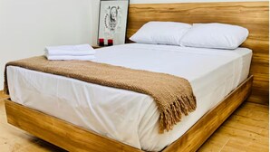 Un lit en bois avec du linge de lit blanc et une couverture marron.