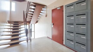 Eine Treppe führt zu einer Zwischenebene, einer roten Tür und mehreren grauen Briefkästen.
