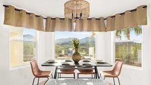 A dining area with a table set for four, a bench, and a view of a mountainous landscape through large windows.