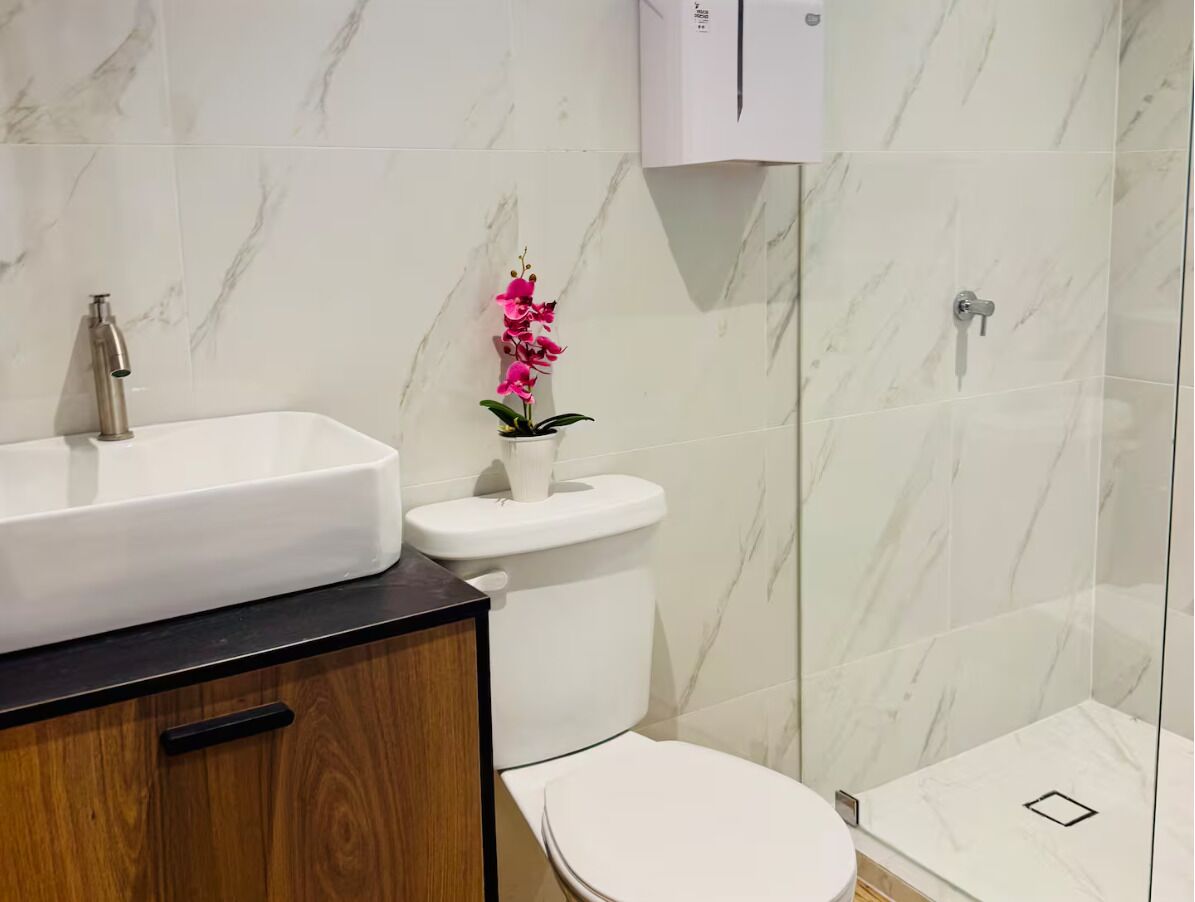 Ein Badezimmer mit weißem Waschbecken, einer Toilette und einer Dusche.
