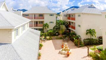 A hotel courtyard with a central fountain, multiple balconies, and lush greenery.