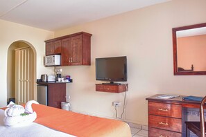 A hotel room with a bed, a television, a microwave, a small desk, and a cabinet.