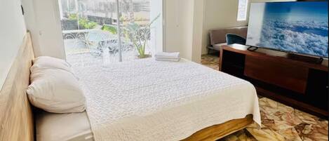 Una habitación de hotel con cama, televisión, escritorio y vistas al exterior.