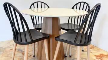 A round table with a wooden base surrounded by four black chairs with wooden legs.