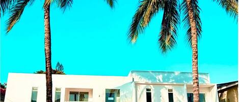 Un edificio de dos pisos con balcones, rodeado de palmeras.