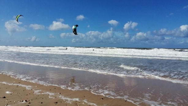 Una playa con olas y cometas.