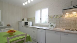 Una cocina con microondas, lavavajillas, pileta y ventana con vista.