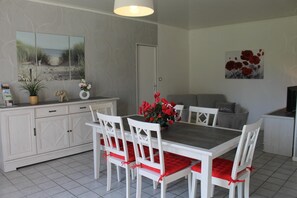 Ein Essbereich mit weißem Tisch und Stühlen, einer Topfpflanze und einem Bild an der Wand.