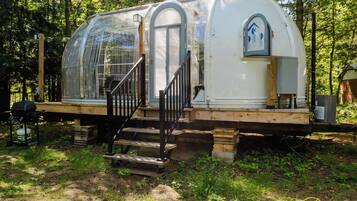 Une maison mobile en forme de dôme, dotée d’un porche couvert et d’un escalier menant à l’entrée.