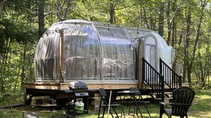 Un camping-car équipé d’une terrasse, d’un barbecue et de mobilier d’extérieur.
