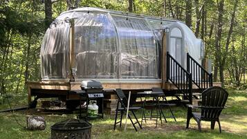 Un camping-car équipé d’une terrasse, d’un barbecue et de mobilier d’extérieur.