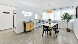 A modern dining area with a table, chairs, a potted plant, and a hanging light fixture. - 3BR Near Restaurants & Nightlife Sleeps 7 (San Juan)