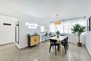 A modern dining area with a table, chairs, a potted plant, and a hanging light fixture. - 3BR Near Restaurants & Nightlife Sleeps 7 (San Juan)