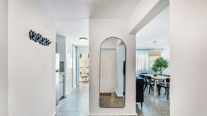 A hallway with a mirror, a dining area with chairs and a table, and a kitchen area with cabinets and a refrigerator. - 3BR Near Restaurants & Nightlife Sleeps 7 (San Juan)