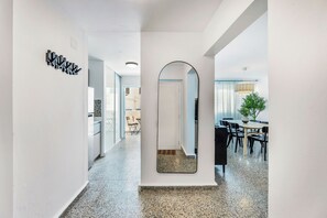 A hallway with a mirror, a dining area with chairs and a table, and a kitchen area with cabinets and a refrigerator. - 3BR Near Restaurants & Nightlife Sleeps 7 (San Juan)