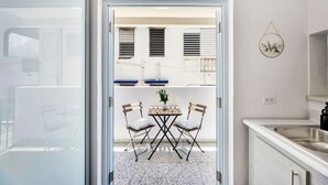 A modern kitchen with a white countertop, a stainless steel sink, and a small dining area with two chairs and a table. - 3BR Near Restaurants & Nightlife Sleeps 7 (San Juan)