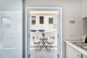 A modern kitchen with a white countertop, a stainless steel sink, and a small dining area with two chairs and a table. - 3BR Near Restaurants & Nightlife Sleeps 7 (San Juan)