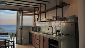 Una cocina moderna con vistas al mar, electrodomésticos integrados y un comedor con mesa y sillas.